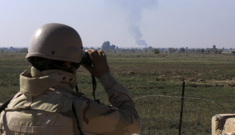 In this Tuesday, Nov. 13, 2018 photo, an Iraqi soldier watches smoke rising after an airstrike by US-led International coalition warplanes against ISIS, on the border between Syria and Iraq in Qaim, Anbar province, Iraq. More than a year after this Iraqi town was freed from the Islamic State group, booms from airstrikes still echo and columns of smoke are visible, rising beyond the earthen berms and concrete walls marking the border with Syria. On the other side, the fight is raging to capture one of the militant groupâs last enclaves.