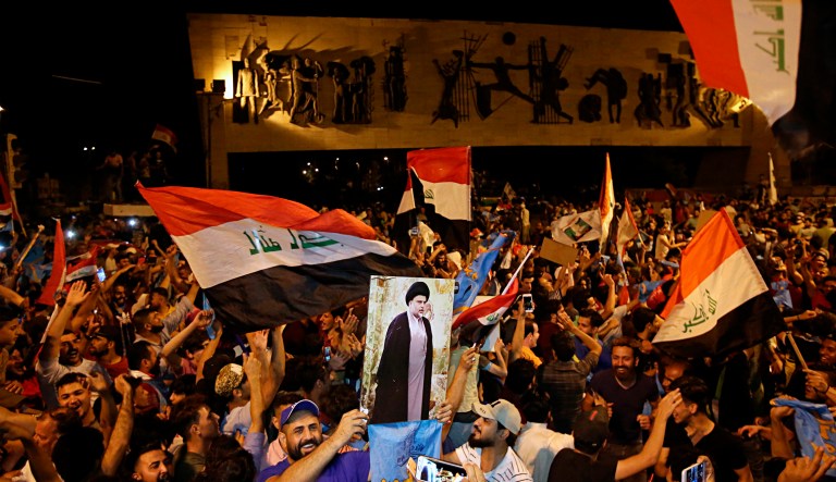 Followers of Shiite cleric Muqtada al-Sadr, displayed on the poster, celebrate in Tahrir Square, Baghdad, Iraq, early Monday, May 14, 2018. The political coalition of influential Shiite cleric Muqtada al-Sadr took an early lead in Iraq's national elections in partial returns announced late Sunday by the Iraqi electoral commission.