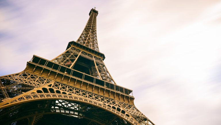 The Eiffel Tower in Paris, France, with blurred moving evening clouds passing behind.