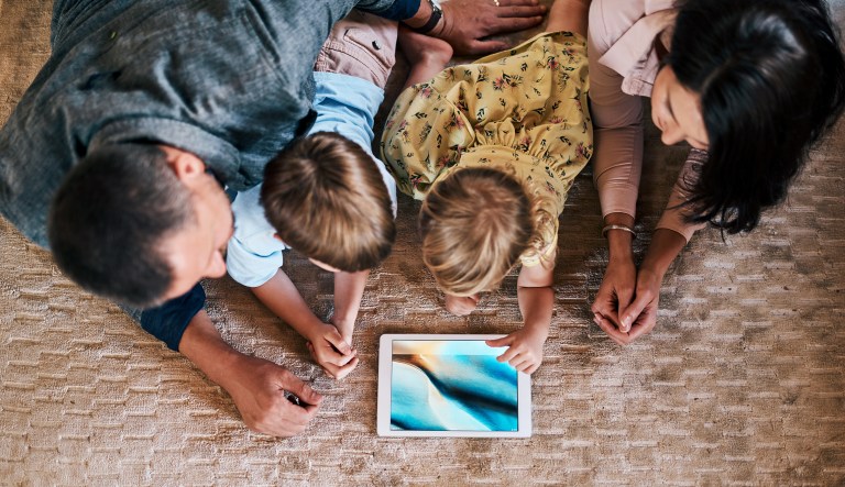 Shot of a young family of four using a digital tablet together at home.