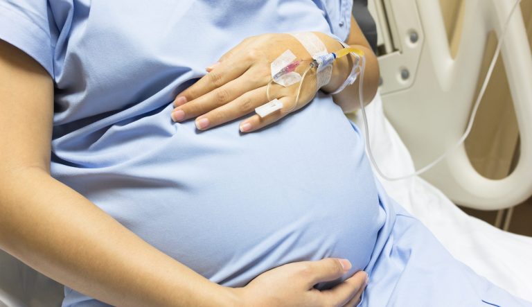 A pregnant woman hooked to an IV in the hospital.