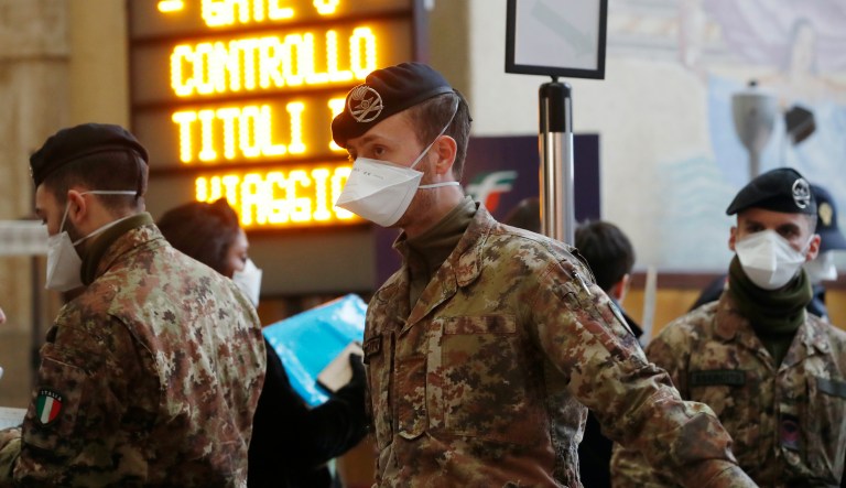 Police officers and soldiers check passengers leaving from Milan main train station, Italy, Monday, March 9, 2020.