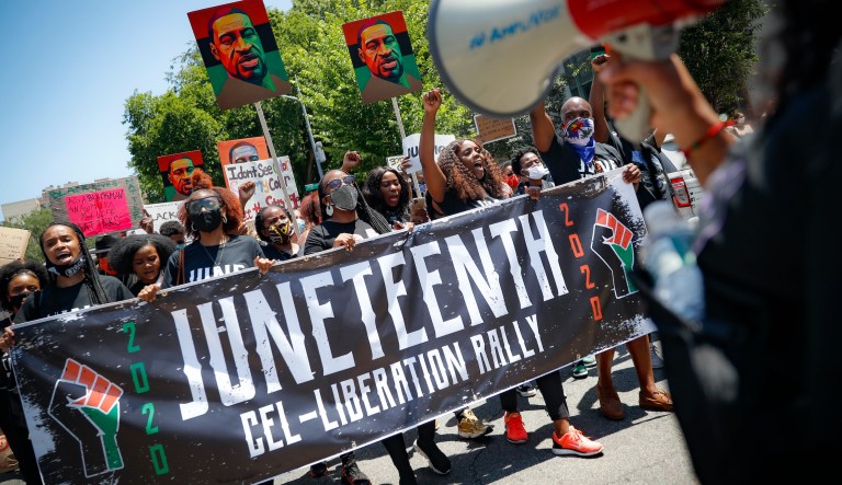 Domino Holmes, left, of Dallas, and Chana Olse, of Ft. Worth, look at images on a phone in front of a Juneteenth balloon set at the inaugural Juneteenth on Main Block Party, in the Deep Ellum neighborhood of Dallas, on Sunday, June 18, 2023.