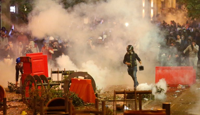 Anti-government protesters clash with the riot police, during a protest near the parliament square, in downtown Beirut, Lebanon, Sunday, Dec. 15, 2019.