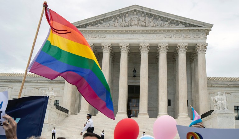 Supporters of the LGBT wave their flag in front of the U.S. Supreme Court, Tuesday, Oct. 8, 2019, in Washington.  The Supreme Court is set to hear arguments in its first cases on LGBT rights since the retirement of Justice Anthony Kennedy. Kennedy was a voice for gay rights while his successor, Brett Kavanaugh, is regarded as more conservative. 