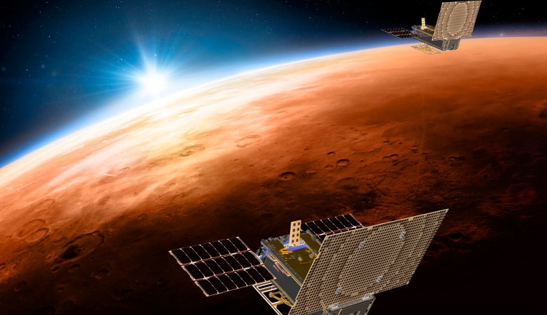 This illustration made available by NASA on March 29, 2018 shows the twin Mars Cube One (MarCO) spacecraft flying over Mars with Earth and the sun in the distance. The MarCOs will be the first CubeSats - a kind of modular, mini-satellite - flown into deep space. They're designed to fly along behind NASA's InSight lander on its cruise to Mars.