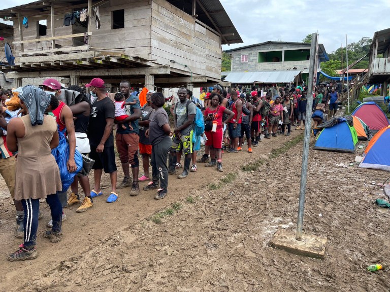 Migrants line up for services at a village after making it through the Darien Gap