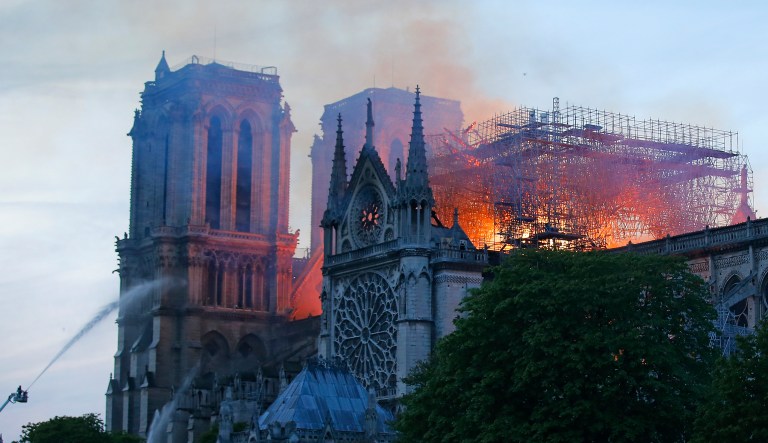 A firefighter tackles the blaze as flames and smoke rise from Notre Dame cathedral as it burns in Paris, Monday, April 15, 2019. Massive plumes of yellow brown smoke is filling the air above Notre Dame Cathedral and ash is falling on tourists and others around the island that marks the center of Paris.