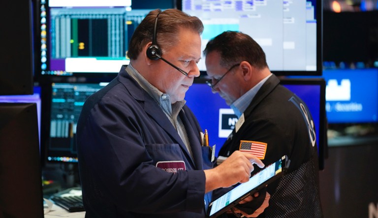 Trader Gregory Rowe, center, and specialist Peter Kennedy, right, check prices as they work on the floor of the New York Stock Exchange Tuesday, March 13, 2012. Strong February retail sales results drove U.S. stocks higher at the opening of trading. 
