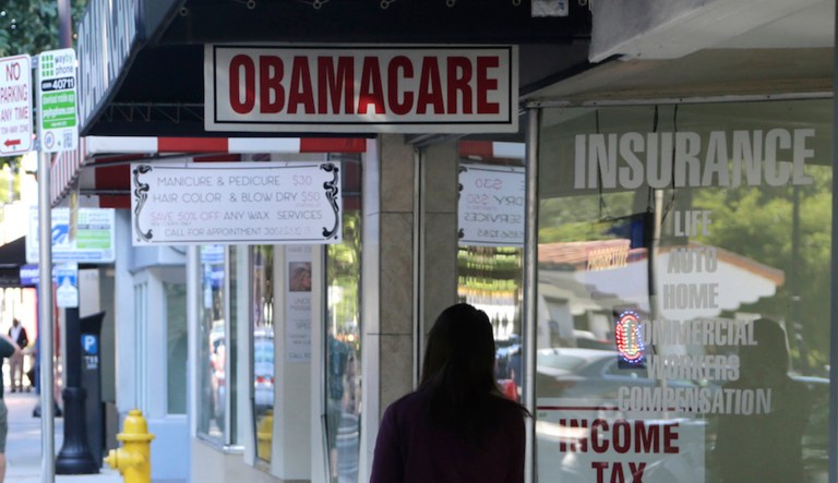 A woman walks past a sign advertising "Obamacare", Tuesday, Jan. 31, 2017, in Miami. The enrollment period for the federal health care law known as "Obamacare" ends at the end of the day Tuesday. The Republican-lead Senate has passed a measure to take the first step forward on dismantling President Barack Obama's health care law. 