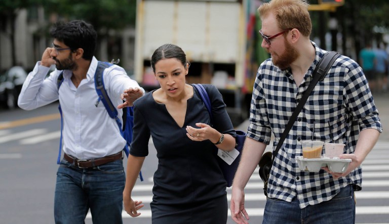 Alexandria Ocasio-Cortez is escorted between interviews by men who worked on her campaign in New York, Wednesday, June 27, 2018. The 28-year-old political newcomer who upset U.S. Rep. Joe Crowley in New York's Democrat primary says she brings an "urgency" to the fight for working families. 