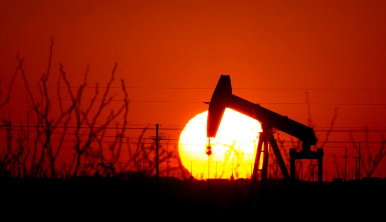 A pump jack operates as the Sun begins to set on the western horizon Monday, March 7, 2022, near Pleasant Farms, an unincorporated community in southeastern Ector County, Texas.  Oil prices are rising sharply again Tuesday as the U.S. prepares to ban crude oil imports from Russia in response to that country's unprovoked invasion of neighboring Ukraine. 