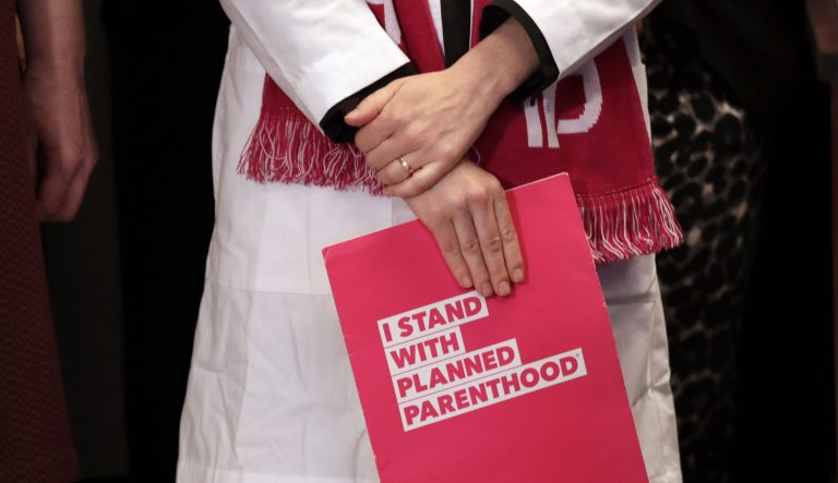 Dr. Erin Berry, Washington State Medical Director for Planned Parenthood of the Great Northwest and the Hawaiian Islands, holds a folder as she listens at a news conference announcing a lawsuit challenging the Trump administration's Title X "gag rule" Monday, Feb. 25, 2019, in Seattle. The rule issued last Friday would impact federal funding for reproductive health care and family planning services. 