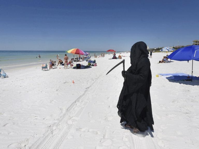 Florida Attorney Daniel Uhlfelder, dressed as the Grim Reaper, walks the newly-opened beach near Destin, Fla.,  Friday, May 1, 2020. Uhlfelder was protesting the Walton County, Fla., Commission's decision to reopen the county's beaches in spite of the COVID-19 pandemic. "In these circumstances, I can see no rational reason to open our beaches, effectively inviting tens of thousands of tourists back into our community," Uhlfelder said in a news release. "If by dressing up as the "Grim Reaper" and walking our beaches I can make people think and potentially help save a life â that is the right thing to do." (Devon Ravine/Northwest Florida Daily News via AP)