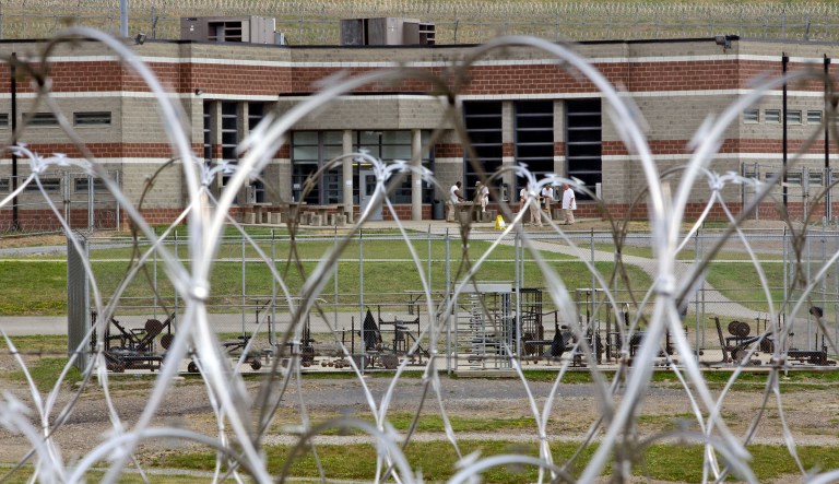 In this Tuesday, July 3, 2012 photo, inmates walk in the yard in front of a cellblock at the maximum-security Mount Olive Correctional Center in Mount Olive, W.Va. In southern West Virginia, they often go to the coal mines. In the northern counties, they go to the oil and gas industry. But everywhere, corrections officers are fleeing the state's regional jails and prisons for better-paying jobs. With the 49th-lowest starting salary in the nation, it's no surprise.