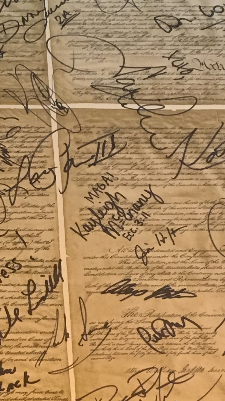 Alongside other signatures, Kayleigh McEnany writes “MAGA!” above her name on a copy of the U.S. Constitution.