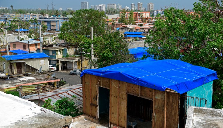 FILE - In this Oct. 19, 2017 file photo, homes in the Cantera area are covered with FEMA tarps, where buildings from the Hato Rey area stand in the background in San Juan, Puerto Rico.