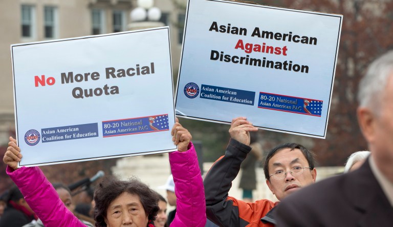 Guixue Zhou of North Potomac, Md., left, and Samuel Yan, of Loudoun County, Va., protest against racial quotas during a rally outside the Supreme Court in Washington, Wednesday, Dec. 9, 2015, as the court hears oral arguments in the Fisher v. University of Texas at Austin affirmative action case. At right is Rep. Dana Rohrabacher, R-Calif., speaking in solidarity with the Asian American Coalition for Education protest.