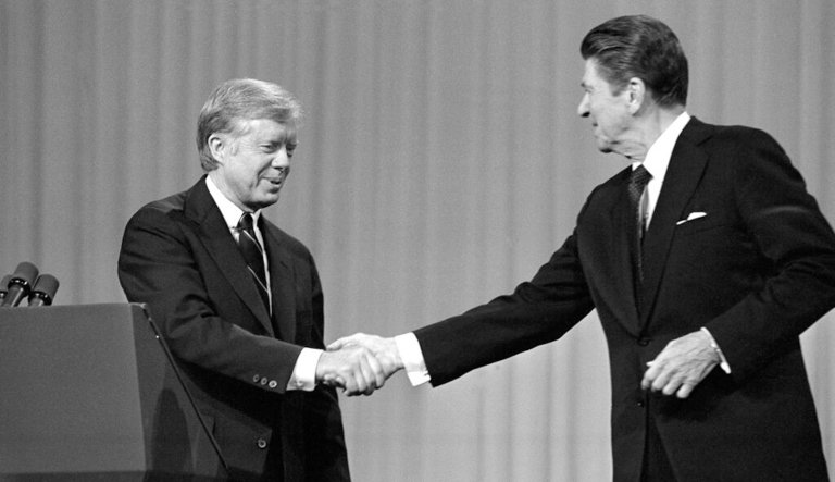 This Oct. 28, 1980, black-and-white file photo shows President Jimmy Carter, left, and Republican Presidential candidate Ronald Reagan shake hands after debating in the Cleveland Music Hall in Cleveland.