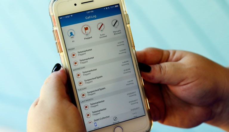 In this Tuesday, Aug. 1, 2017 photo, Jen Vargas checks out an AT&T app on her cell phone at her home in Orlando, Fla. The app helps locate and block fraudulent calls although some robocalls still get through. (AP Photo/John Raoux)