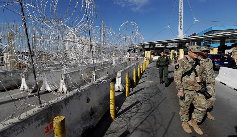 U.S. Border Patrol agents and members of the military pass concertina wire during a tour of the San Ysidro port of entry Friday, Nov. 16, 2018, in San Diego.