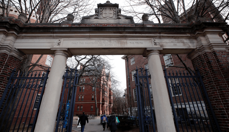 FILE - In this Dec. 13, 2018 file photo, people walk through the gates leading to Harvard Yard at Harvard University in Cambridge, Mass. Harvard's student newspaper is facing a campus backlash over a routine request for government comment about a student demonstration against U.S. Immigration and Customs Enforcement. (AP Photo/Charles Krupa, file)