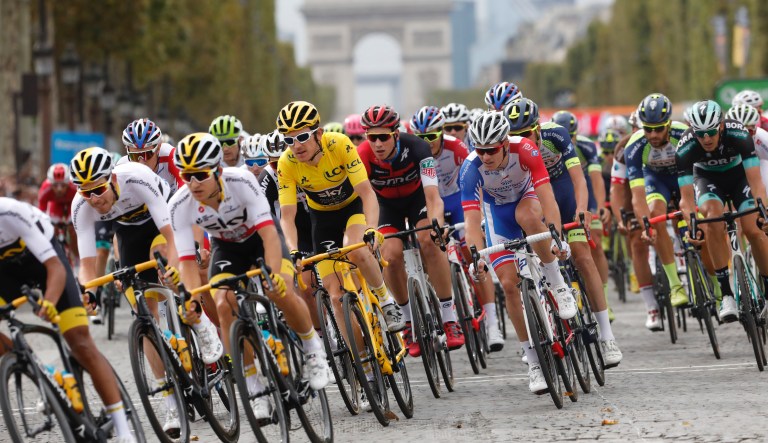 Tour de France winner Britain's Geraint Thomas, wearing the overall leader's yellow jersey, follows teammate Poland's Michal Kwiatkowski, second left, and Britain's Luke Rowe, left, as they ride down Chams Elysees avenue as the Arc de Triomphe is seen in the background during the twenty-first stage of the Tour de France cycling race over 116 kilometers (72.1 miles) with start in Houilles and finish on Champs-Elysees avenue in Paris, France, Sunday July 29, 2018. 