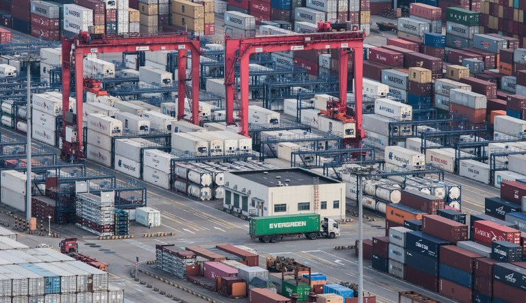 A cargo truck drives amid stacked shipping containers at the Yangshan port in Shanghai, Thursday, March 29, 2018. China's Commerce Ministry called on Washington on Thursday to discard planned tariffs it warned might set off a chain reaction that could disrupt global trade and said Beijing will "fight to the end".