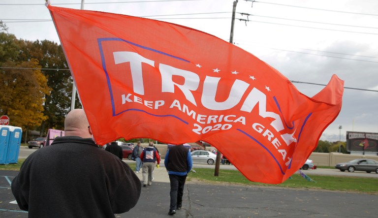 A Trump supports carries a flag as he makes his way to a campaign rally featuring President Donald Trump in Indianapolis, Friday, Nov. 2, 2018.