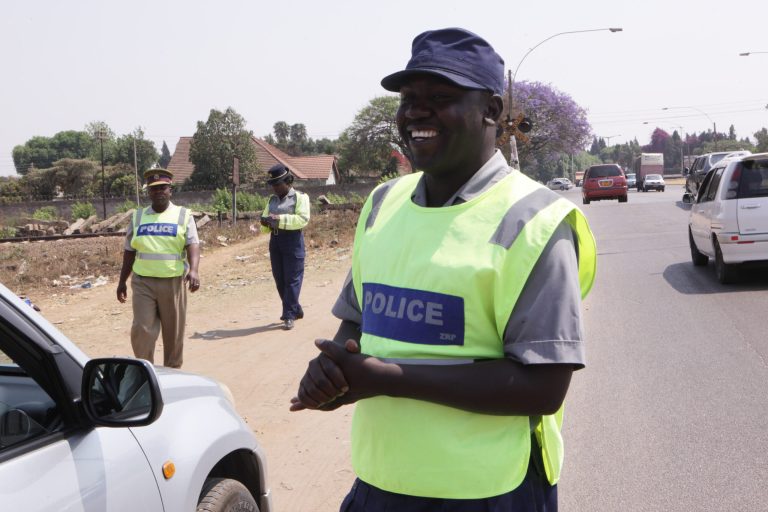A police officer smiles after stopping a vehicle in Harare, Friday, Oct. 3, 2014 on World Smile Day.  According to  Zimbabwe's deputy Minster of Home Affairs Ziyambi Ziyambi whose ministry is in charge of the police, the hospitality agency would conduct 