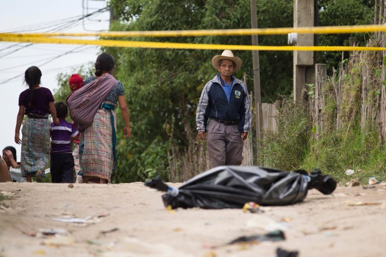 A resident pauses to look at a taped off area, where a body lies wrapped in a black bag, in Pajoques, Guatemala, Saturday, Sept. 20, 2014. An argument over plans to build a factory and highway in the village west of Guatemala City provoked a violent clash late Friday that has left at least six people dead and dozens of others seriously wounded. (AP Photo/Moises Castillo)