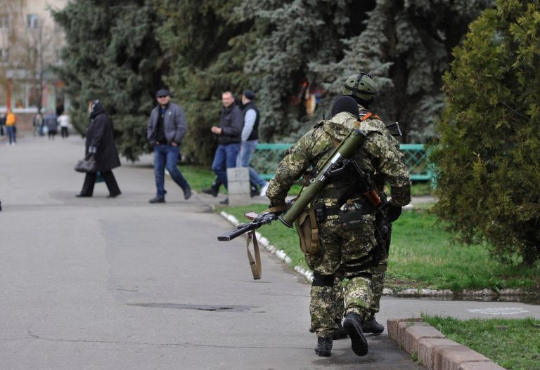 Armed pro-Russian activists walk through a street near to the seized Ukrainian regional administration building in the eastern Ukrainian town of Slovyansk,  Ukraine, Monday, April 14, 2014.  Ukraine's acting president urged the United Nations on Monday to send peacekeeping troops to eastern Ukraine, where pro-Russian gunmen kept up their rampage of storming and occupying local government offices, police stations and a small airport. (AP Photo/Evgeniy Maloletka)