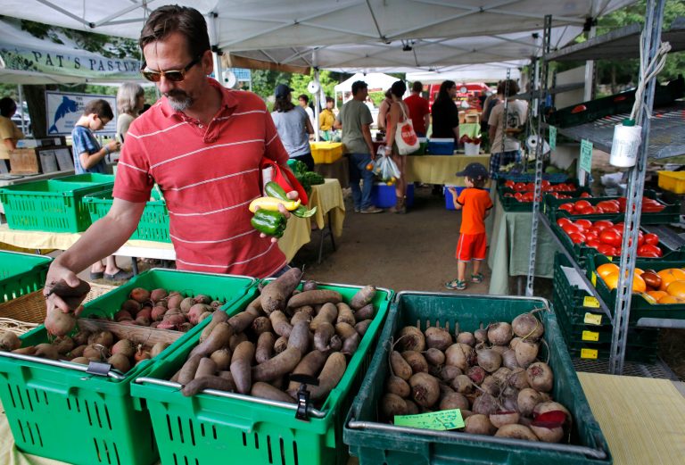 FILE - In this July 30, 2014 photo, David Mann, of Pawtucket, R.I., shops for vegetables at the Wishing Stone Farm stand at a farmers market, in Providence, R.I. The Commerce Department reports on wholesale stockpiles and sales in August on Thursday, Oct. 9, 2014. (AP Photo/Steven Senne, File)