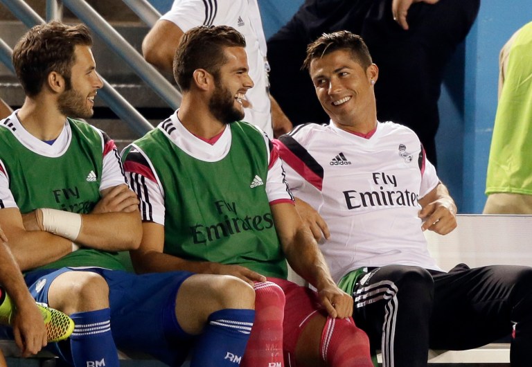 Real Madrid's Cristiano Ronaldo, right, smiles as he talks with teammates on the bench in the first half of a Guinness International Champions Cup soccer tournament match, Tuesday, July 29, 2014, in Dallas. (AP Photo/Tony Gutierrez)