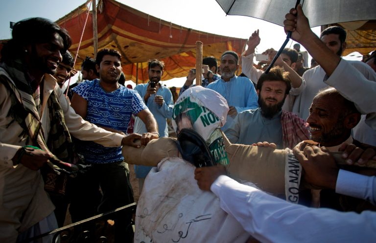 Supporters of Pakistan's cricketer-turned politician, Imran Khan, beat an effigy of Pakistani prime minister Nawaz sharif during a sit-in protest outside a parliament building in Islamabad, Pakistan, Monday, Oct. 6, 2014. Anti-government protesters led by opposition leaders Khan and Muslim cleric Tahir-ul-Qadri converged on the capital in mid-August, demanding Sharif's ouster over alleged fraud in last year's election. (AP Photo/B.K. Bangash)