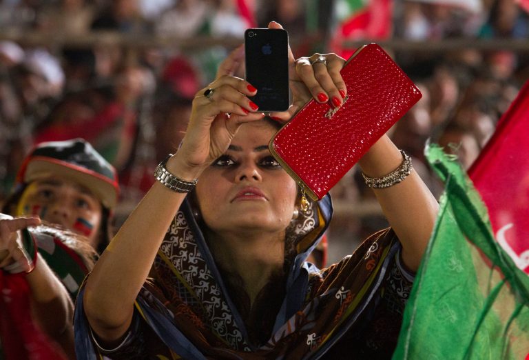 A supporter of Pakistan's cricketer-turned-politician Imran Khan uses her cell phone to take picture of Khan during a protest near the parliament building in Islamabad, Pakistan, Monday, Aug. 25, 2014.  Thousands of supporters of Pakistan's cricketer-turned-politician Imran Khan and Muslim cleric Tahir-ul-Qadri are besieging parliament in the capital to pressure Sharif to resign over alleged election fraud. (AP Photo/Anjum Naveed)
