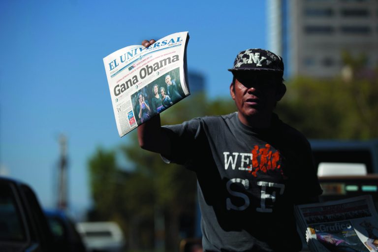 A newspaper vendor sells dailies with the front page showing President Barack Obama that reads in Spanish 