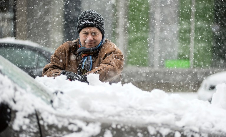 Curt Anderson clears snow off his vechicle in downtown Austin, Minn., Thursday, Feb. 20, 2014 as the winter storm covering the area moves through. (AP/Austin Daily Herald, Eric Johnson)
