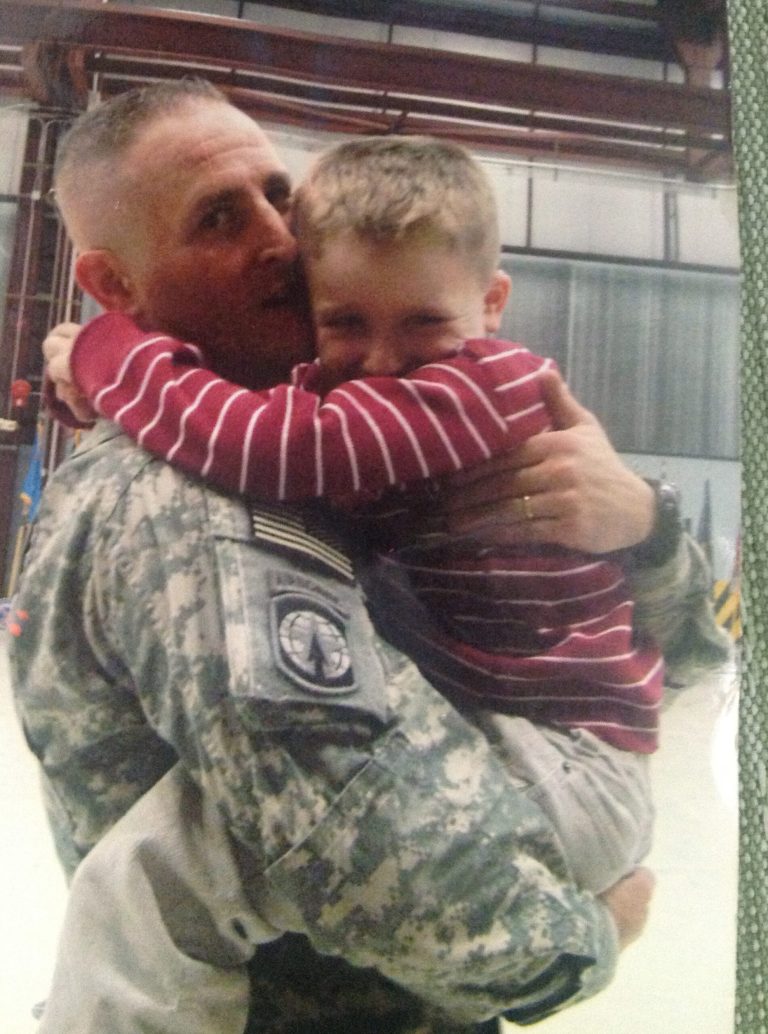 In this 2009 photo provided by Tanya Bartholomew, her husband, former army soldier, Clark Bartholomew, is seen carrying their son Aric at Fort Drum, N.Y. The former soldier's lawsuit alleging he bit into needles in a Burger King sandwich purchased at Hawaii's Schofield Barracks in 2010 is headed to trial in August after a settlement couldn't be reached. (AP Photo/Tanya Bartholomew)