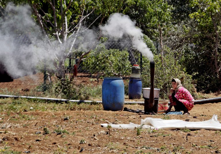 In this Tuesday, April 29, 2014 photo, a Syrian displaced woman prepares food for her family outside their tent, at a Syrian refugee camp, near the eastern town of Kab Elias, Lebanon. Syrian refugees in Lebanon say they must pay bribes to middlemen ranging from $3 to $100 to receive aid, adding another layer of suffering for those fleeing the war, according to a series of interviews with refugees in a tent encampment near the eastern Lebanese town of Kab Elias this month. (AP Photo/Bilal Hussein)