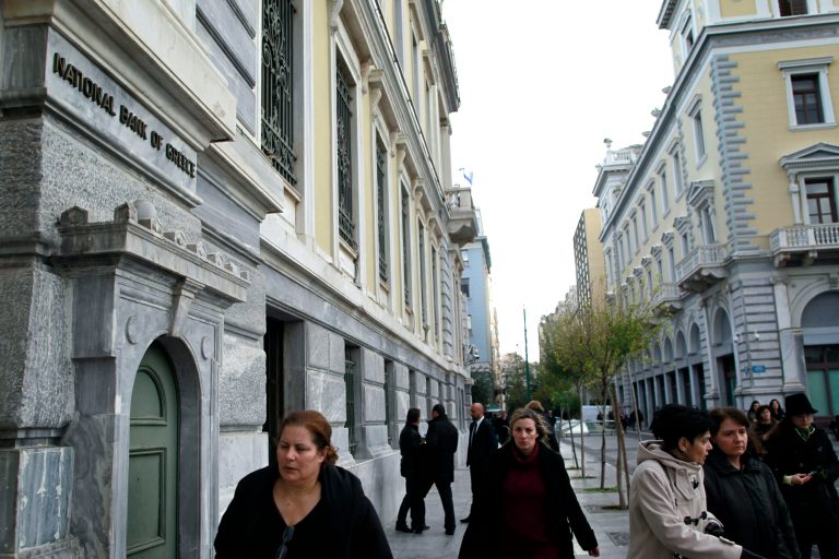   Athenians walk past a central Athens branch of National Bank of Greece, the country's largest lender, Tuesday, Dec. 11, 2012. Greece was expected to announce later Tuesday the results of a bond buyback hoped to cut some 20 billion euros off the country's 340 billion euro debt load. Domestic lenders will contribute strongly in the European-funded buyback, which if successful will open the way for disbursement of a delayed international rescue loan payment. (AP Photo/Petros Giannakouris)  