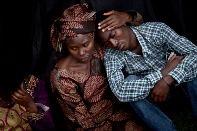 Bizimana Emmanuel, who was born two years before the genocide, is consoled by an unidentified woman while attending a public ceremony to mark the 20th anniversary of the Rwandan genocide, at Amahoro stadium in Kigali, Rwanda,  Monday, April 7, 2014. Sorrowful wails and uncontrollable sobs resounded Monday as thousands of Rwandans packed the country's main sports stadium to mark the 20th anniversary of the beginning of a devastating 100-day genocide. (AP Photo/Ben Curtis)