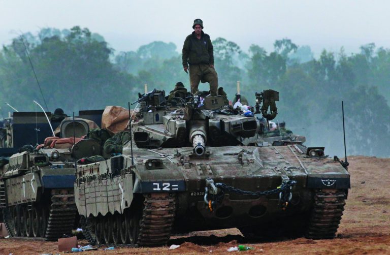 An Israeli soldier stands on a tank at a staging area near the Israel Gaza Strip Border, southern Israel, early Tuesday, Nov. 20, 2012. U.N. Secretary-General Ban Ki-moon is urging Israeli forces and Gaza militants to hold their fire, warning that a further escalation of the seven-day-old conflict would endanger the entire region. (AP Photo/Lefteris Pitarakis)