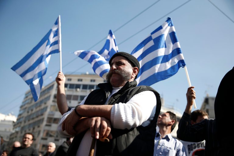 A farmer from the northern Greek region of Pella takes part in a protest against government tax policies as others wave Greek flags behind, in central Athens on Wednesday, Feb. 19, 2014. About 4,000 people, including civil servant unions, took part in the peaceful demonstration outside of the House of Parliament. Greece's conservative-led government has committed to continue spending cuts and economic reforms in exchange for billions of euros in international rescue loans. (AP Photo/Petros Giannakouris)