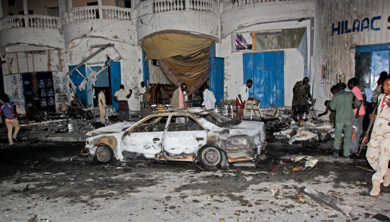 Somali security forces and others attend the scene of a car bomb attack in the capital Mogadishu, Somalia Sunday, Oct. 12, 2014. A car bomb exploded outside the popular Aroma cafe in Somalia's capital killing at least 11 people and wounding a number of others, a senior police official said Sunday, adding that the bomb was believed to have been detonated by remote control. (AP Photo/Farah Abdi Warsameh)