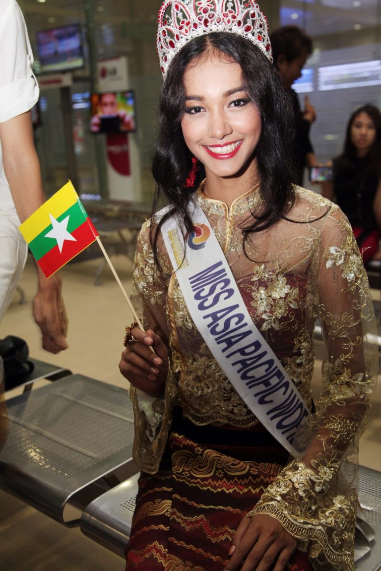 FILE - In this June 5, 2014 file photo, Myanmar model May Myat Noe, winner of Miss Asia Pacific World 2014 pageant, waves a miniature flag of the country upon her arrival at Yangon International Airport in Yangon, Myanmar. The first Myanmar national to win an international pageant has been stripped of her title for being rude and dishonest, and has allegedly run off with the expensive crown and breast implants. (AP Photo/Khin Maung Win)