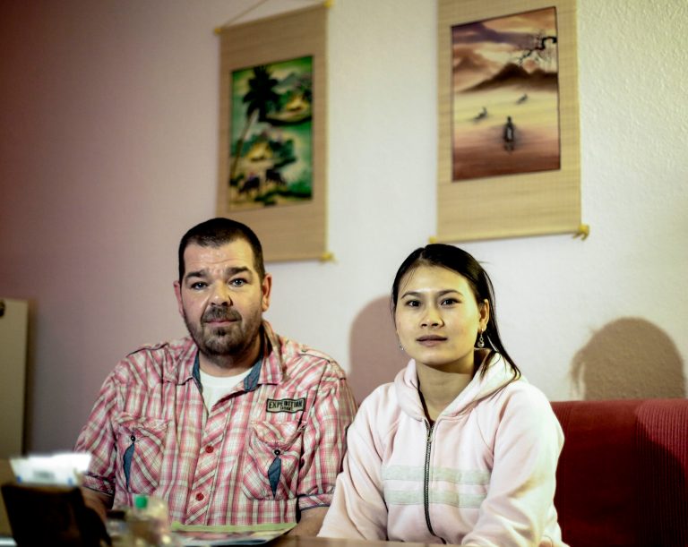 In this picture taken Tuesday, Feb. 11, 2014, Michael Guhle and his wife Thi An Nguyen from Vietnam sit in their apartment at the Weissensee district in Berlin, Germany. Guhle met the love of his life on the beach of a little fishing village in Vietnam. Nguyen was selling freshly cooked mussels and fruit to the German tourist and they immediately clicked. Soon the Berlin nursing home worker was saving up all of his money and vacation days to visit her. Marriage was supposed to bring them together. Instead, it was the beginning of a long ordeal apart. Germany blocked her from entering the country after she flunked the language test that Germany requires aspiring immigrants to pass - even those married to Germans. (AP Photo/Markus Schreiber)