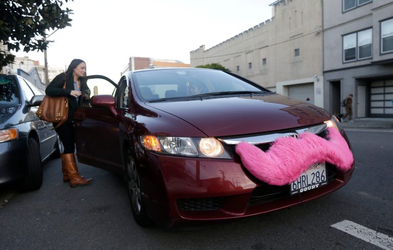 FILE - In this Jan. 4, 2013 file photo, Lyft passenger Christina Shatzen gets into a car driven by Nancy Tcheou in San Francisco. Ride-sharing companies Uber, Lyft and Sidecar are being threatened with legal action in San Francisco and Los Angeles over how they screen drivers and charge passengers.  (AP Photo/Jeff Chiu, File)