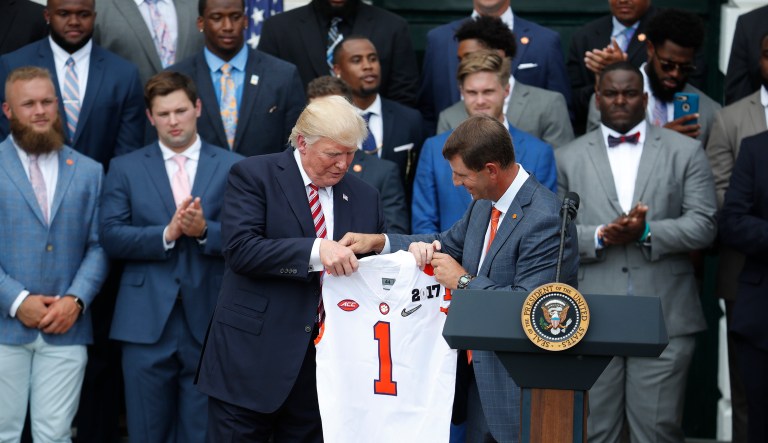 President Donald Trump holds up a jersey given to by head coach Dabo Swinney as he welcomes the 2016 NCAA Football National Champions Clemson University Tigers, Monday, June 12, 2017, during a ceremony on the South Lawn of the White House in Washington. (AP Photo/Pablo Martinez Monsivais)