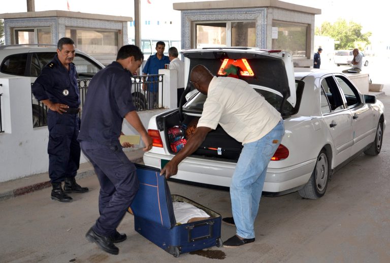 Tunisian custom officers check the luggage of a man fleeing from Libya at the Ras Ajdir border post between Libya and Tunisia, southern Tunisia, Thursday, July 31, 2014. Up to 6,000 people a day have fled Libya into neighboring Tunisia this week, the Tunisian foreign minister said Wednesday, the biggest influx since Libya's 2011 civil war in a sign of the spiraling turmoil as rival militias battle over control of the airport in the capital Tripoli. (AP Photo/Ali Manssour)